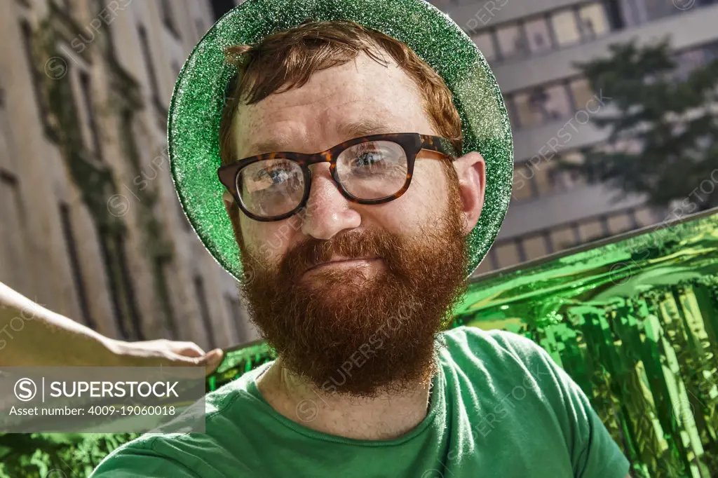 Redheaded man wearing green hat and shirt at St Patrick's Day Party