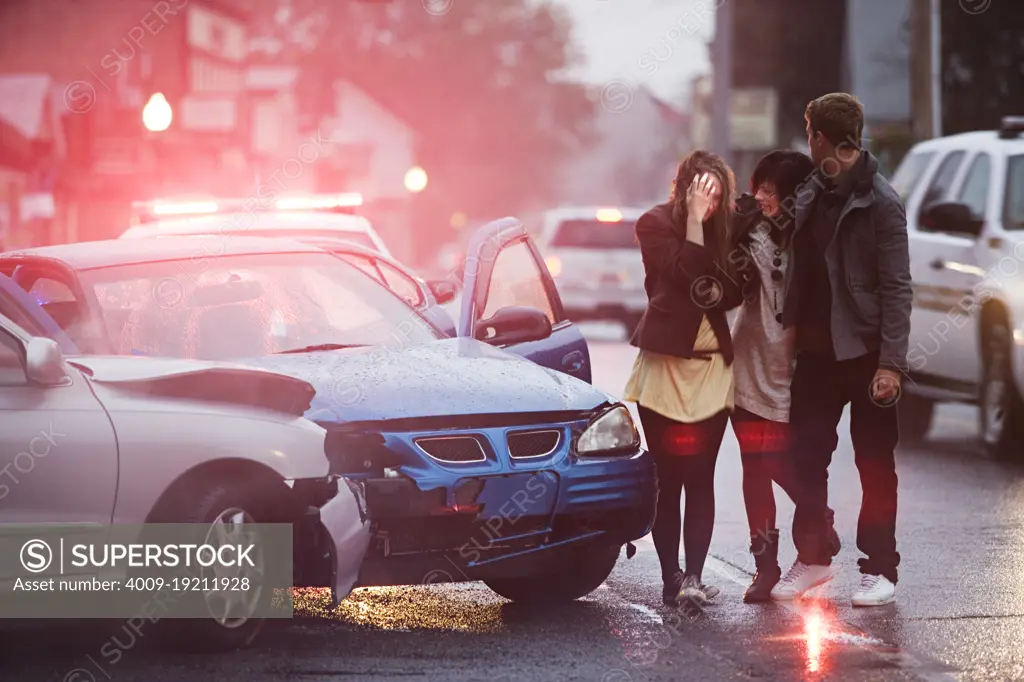 Three young adults walking away from automobile accident