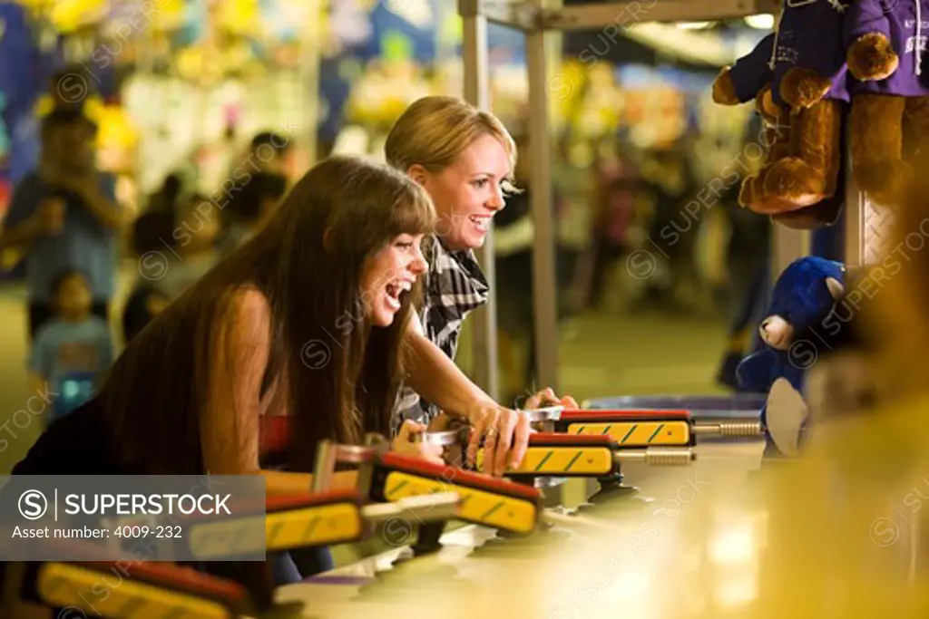 Two female friends playing a game at an amusement park