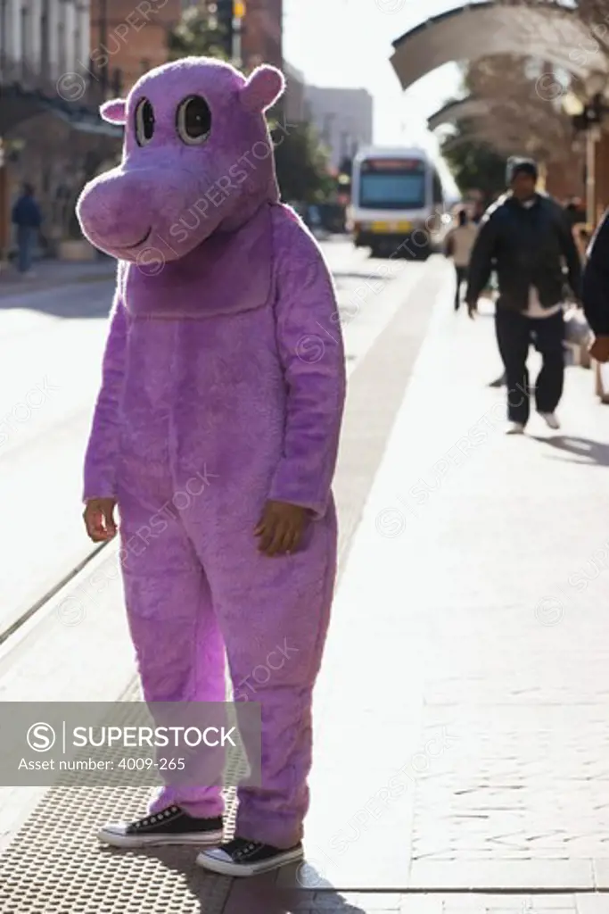 Young man waiting at tram stop in hippo costume