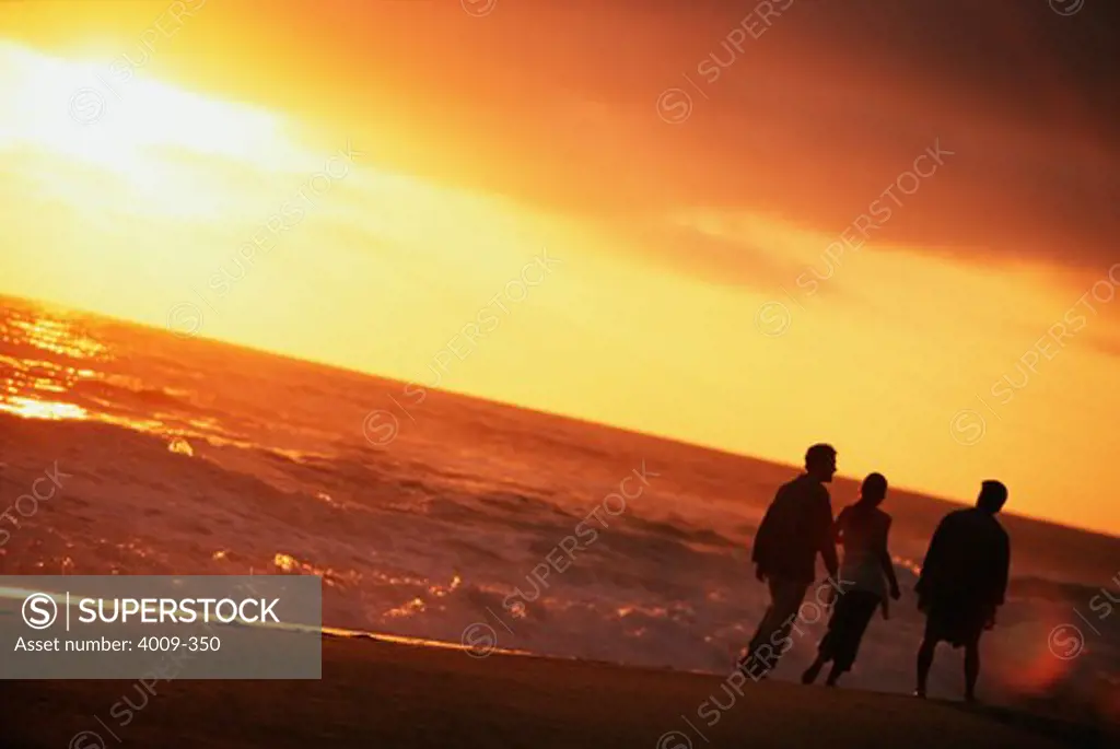 Three tourists walking on the beach