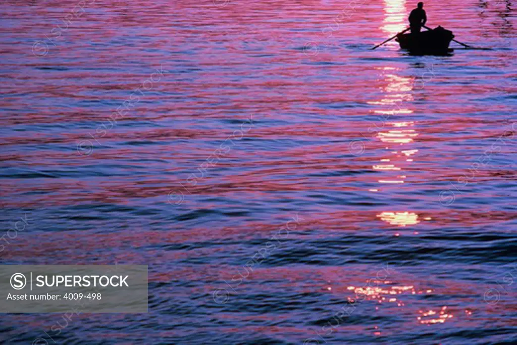 Silhouette of a person in boat at sunset, Anzio, Italy