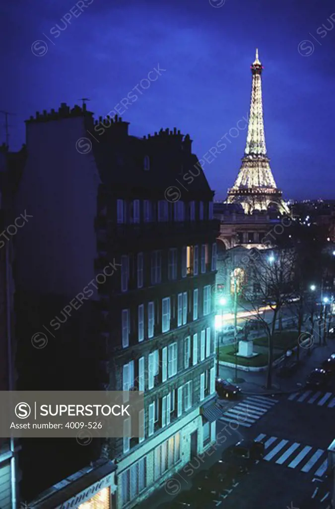 Buildings in a city with a tower lit up in the background, Eiffel Tower, Paris, Ile-de-France, France
