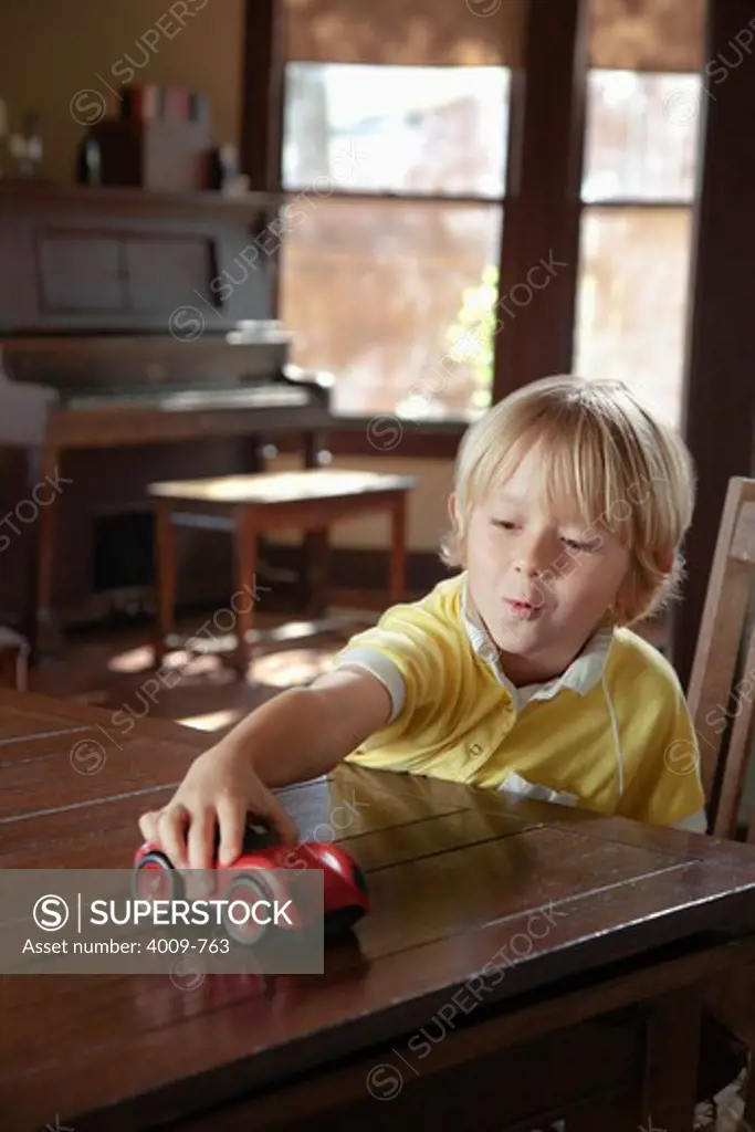 Boy playing with toy car on a table