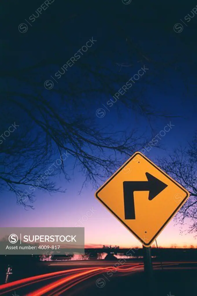 Neon streak of traffic and a sign with right directional arrow at roadside near a lake, White Rock Lake, Dallas, Texas, USA