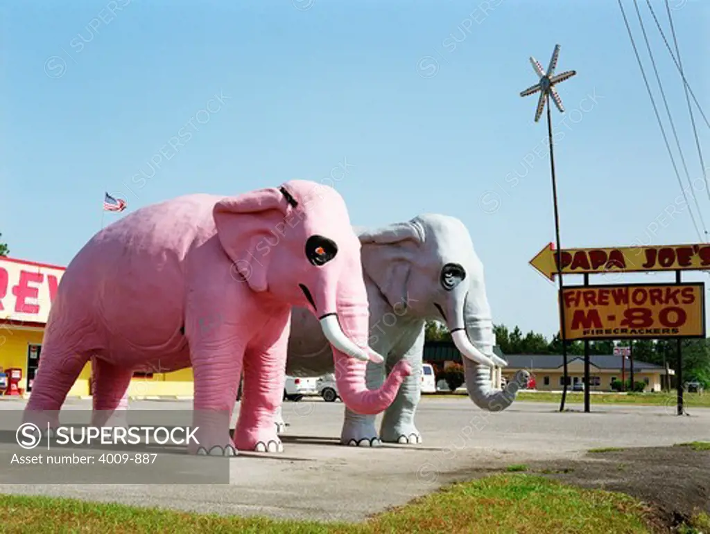 Pink and Gray elephant sculptures standing in front of Papa Joe's firework stand, Hardeeville, South Carolina, USA