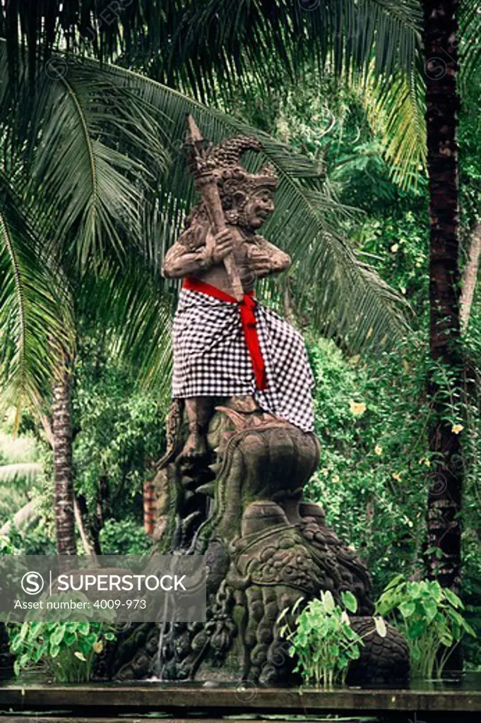 Statue of a warrior wearing a checkered skirt conquering lion in the forest, Bali, Indonesia