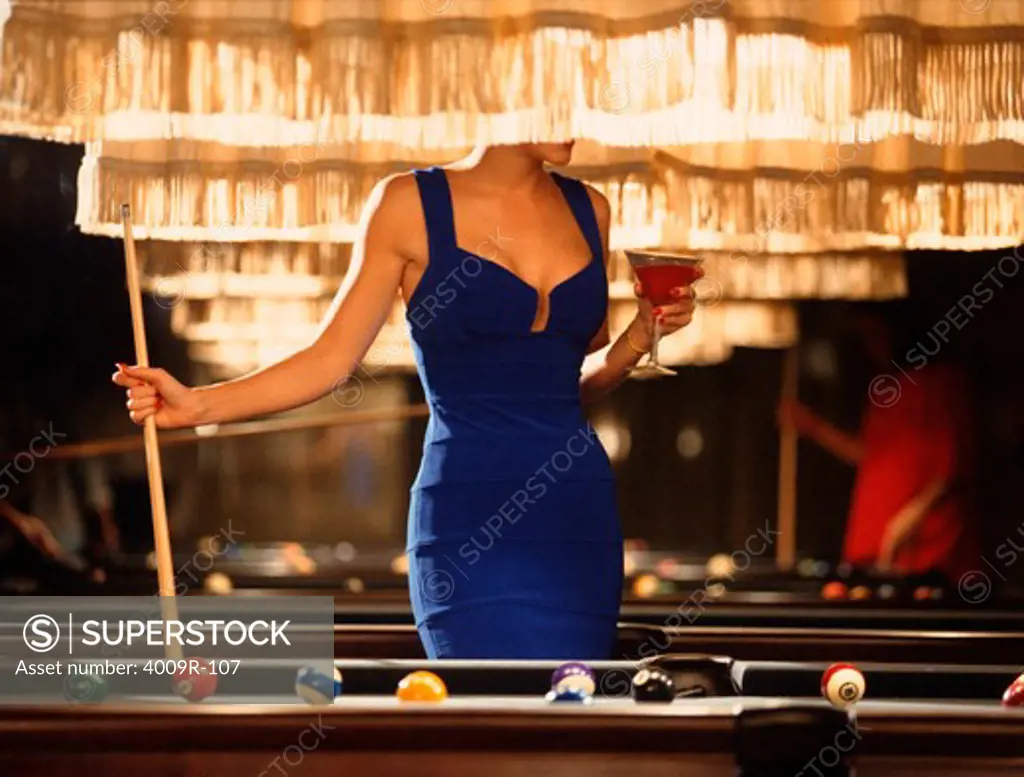 Woman in blue dress playing pool in a bar