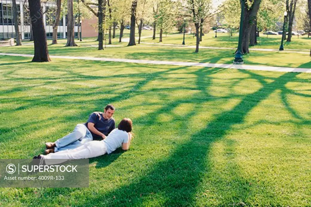Young couple lying on the grass in the university campus