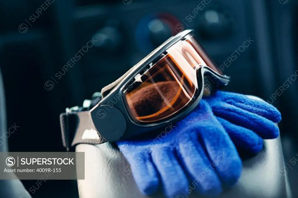 Ski goggles and gloves on an armrest or a car
