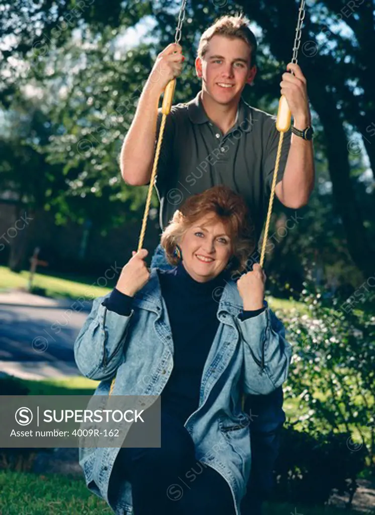 Young man with his mother on a swing
