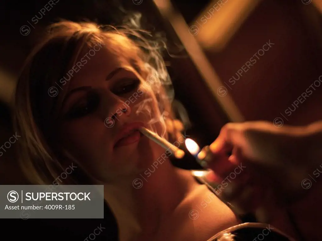 Young woman smoking lighting up a cigarette in a night club