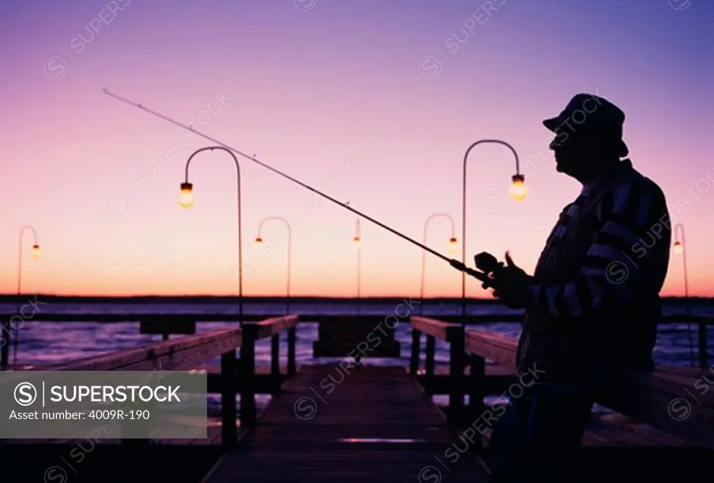 Mature man fishing on a dock in the morning