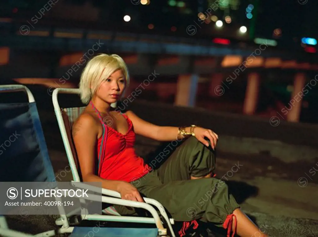 Young woman sitting on roof in night