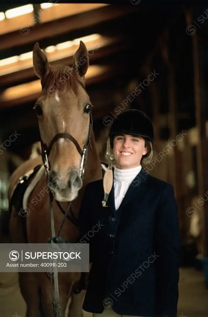 Portrait of a female jockey standing with a horse