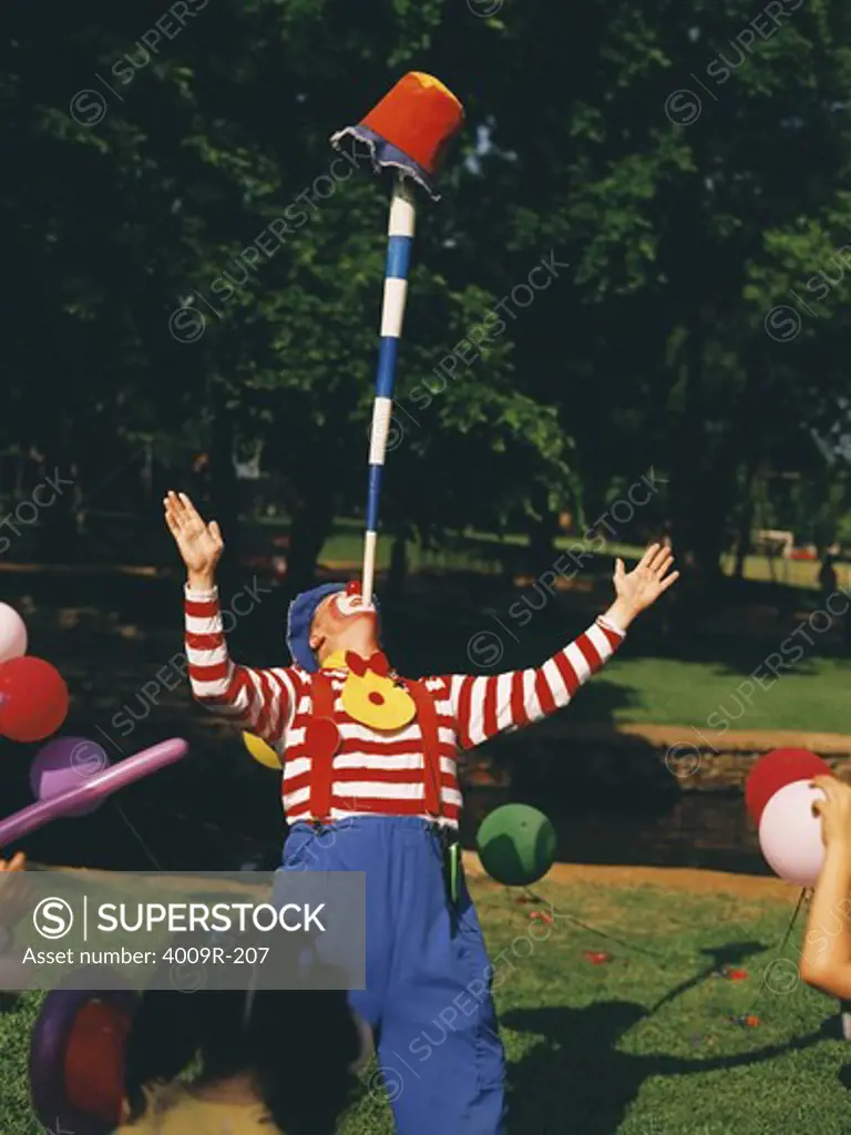 Clown performing a balancing trick with a pole and a bucket in a birthday party