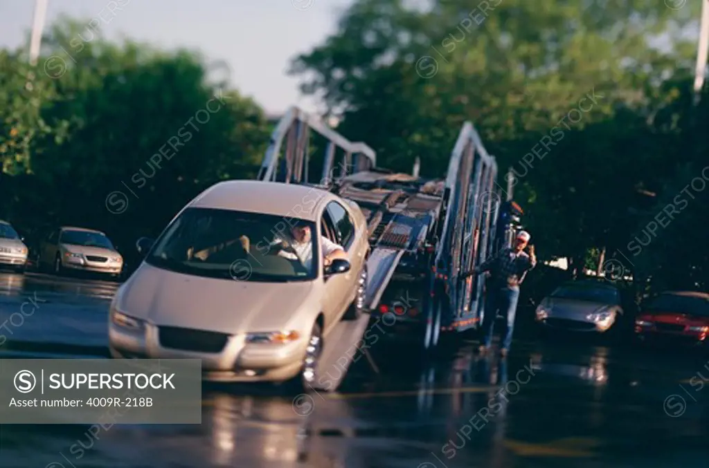 Man supervising the unloading of new cars from a truck