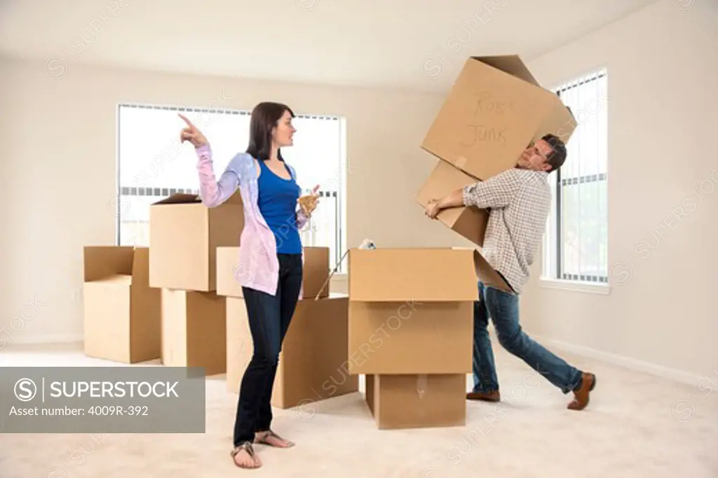 Woman drinking wine while telling her husband to move boxes