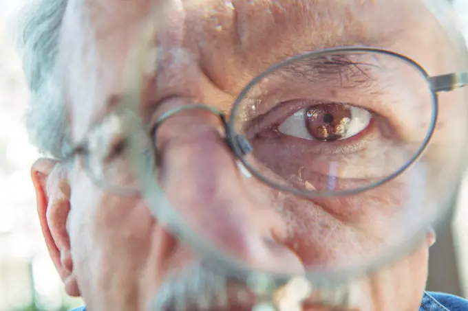 Eye of older man using magnifying glass