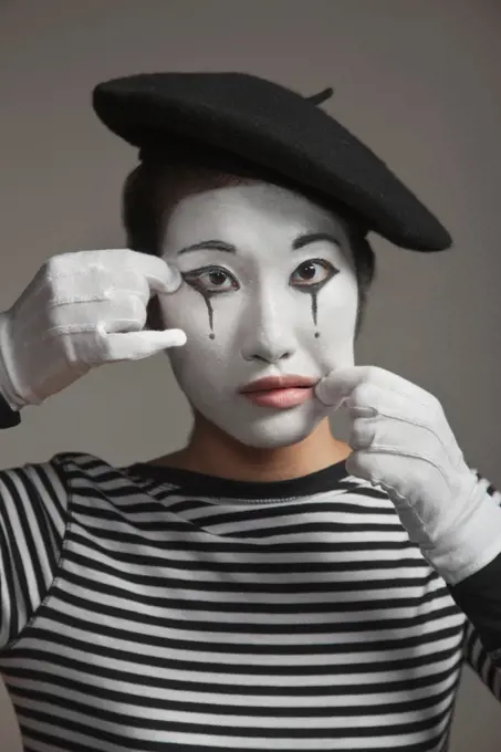 Woman in mime costume stretching her face