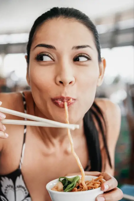 Pilipino woman eating noodles