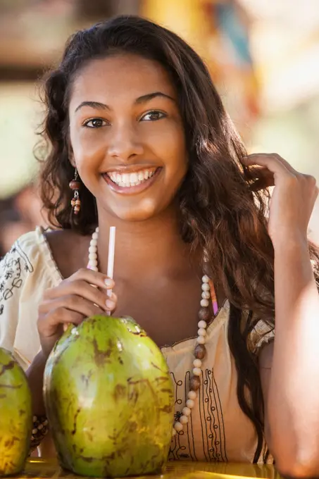 Smiling teenage girl drinking from coconut