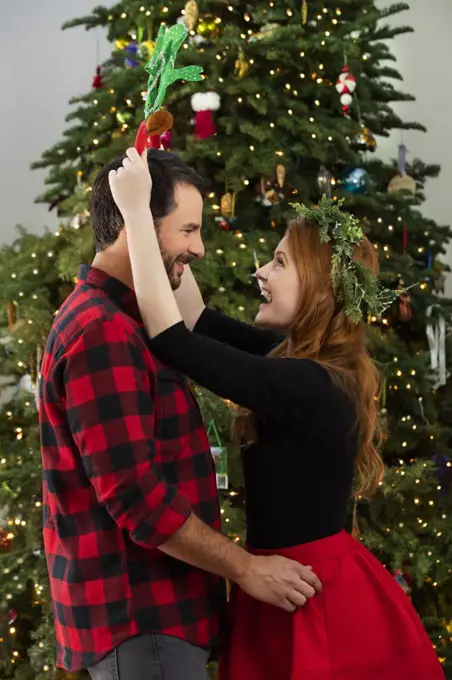 Happy Caucasian couple flirting in front of Christmas tree.