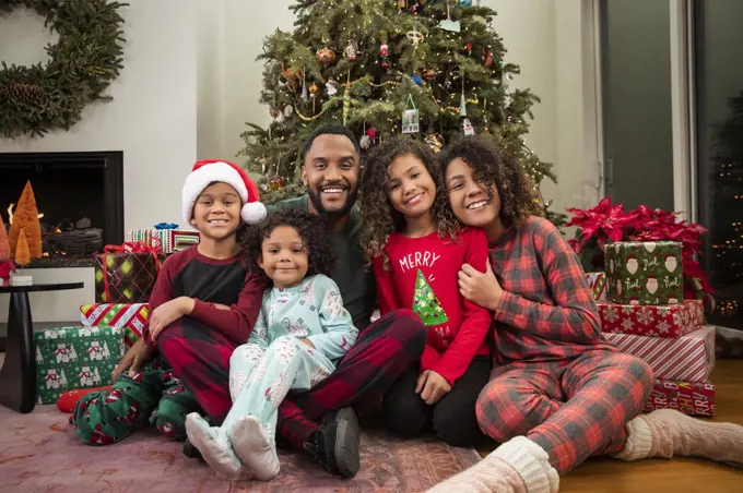 Christmas Card Portrait of a joyful young Black family sitting in front of Christmas tree