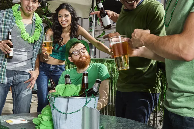 Man sitting down while all his friends party and have fun around him during St Patrick's Day