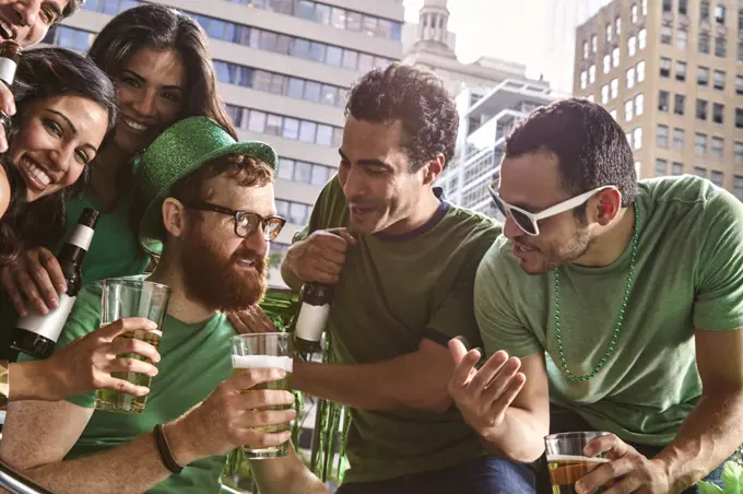 Group of diverse friends toasting while drinking beer and celebrating St Patrick's Day