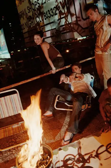 Friends enjoying on a roof around a bonfire