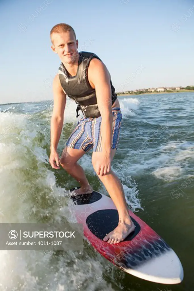 Teenage boy wakeboarding on lake