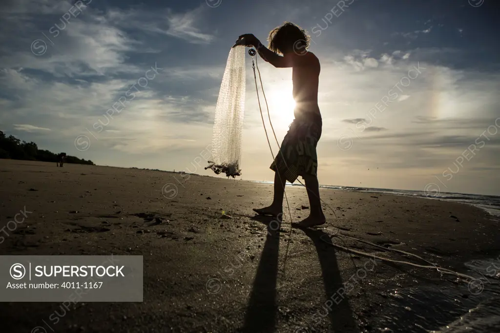 Young boy holding a net to catch bait fish on the beach, Costa Rica