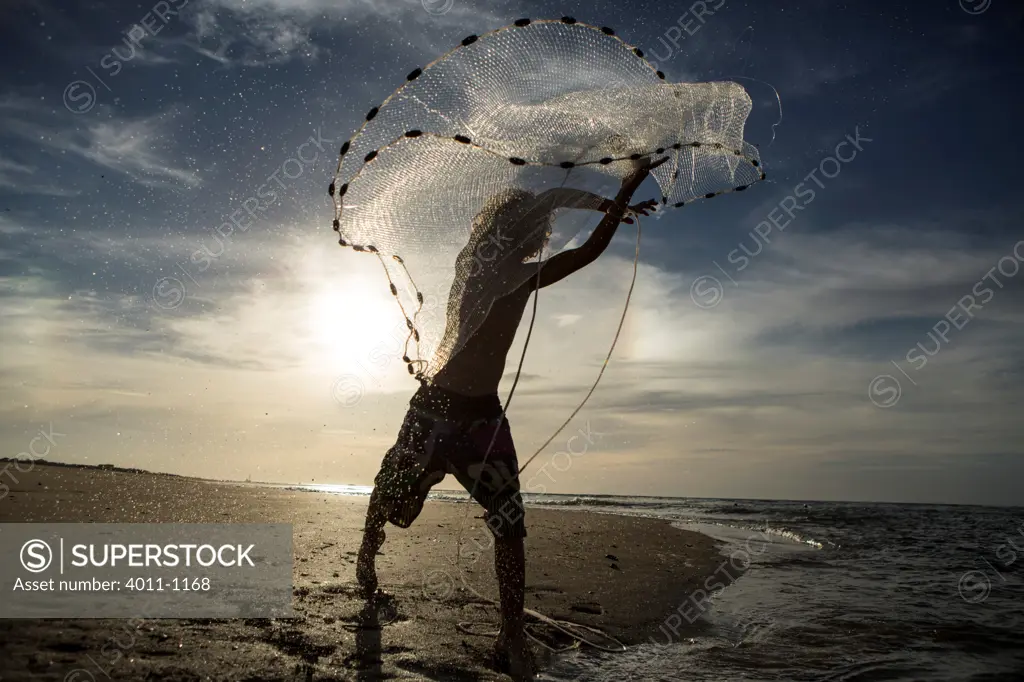 Young boy throwing out fishing net on the beach, Costa Rica