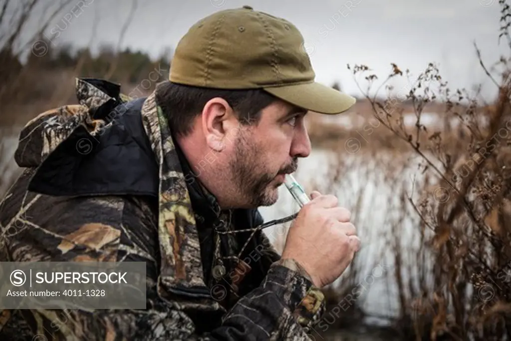 Hunter standing near lake using duck call