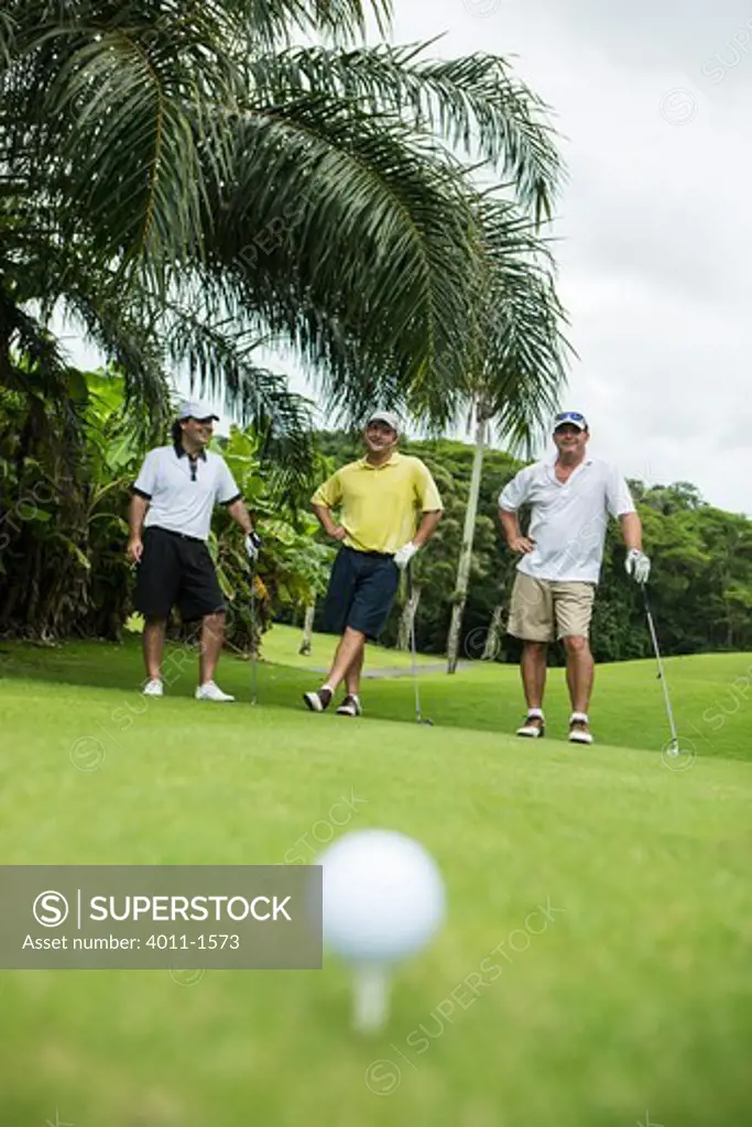 Costa Rica, Golf ball on  tee with three golfers in  background