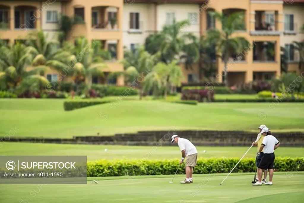 Costa Rica, Three golfers putting on  green