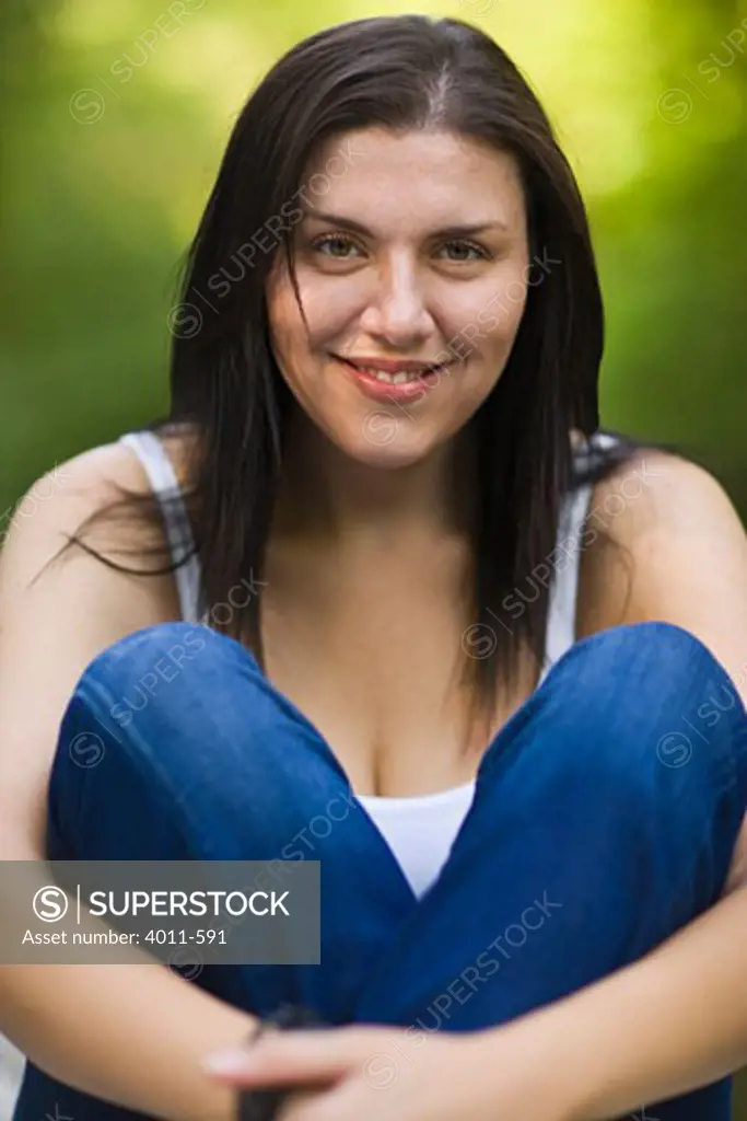 Young woman hugging knees and smiling