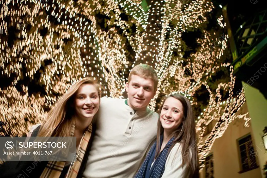 Teenage friends standing in front of a Christmas tree