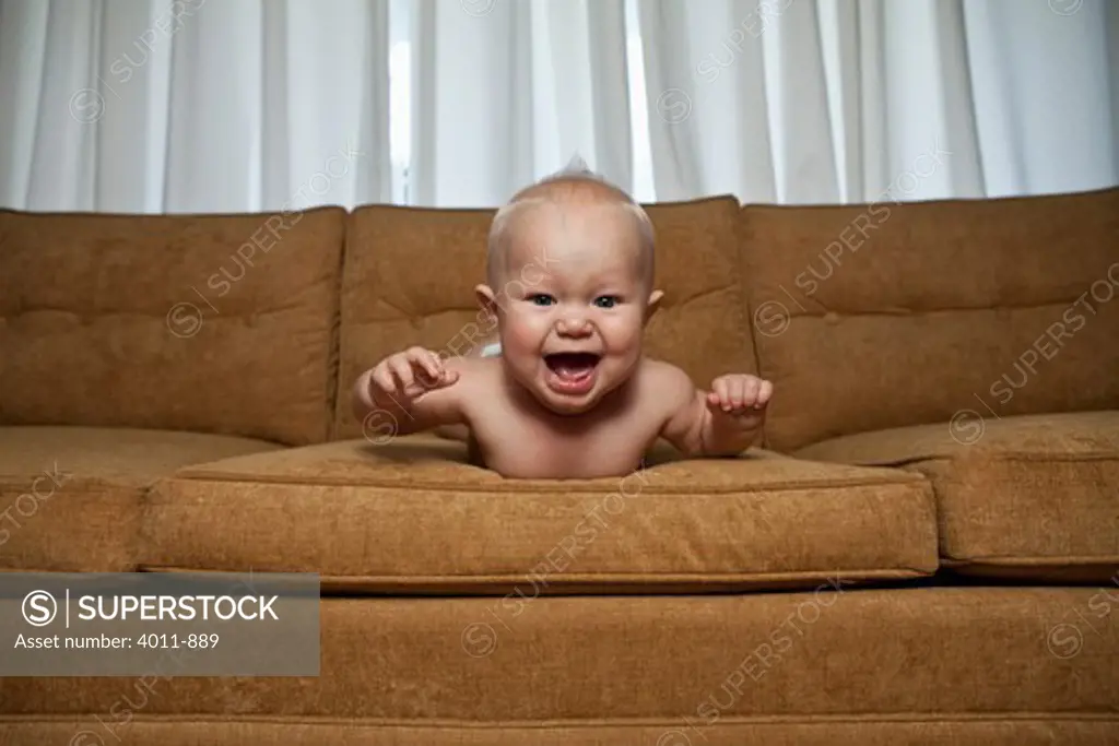 Seven month old baby on couch laughing