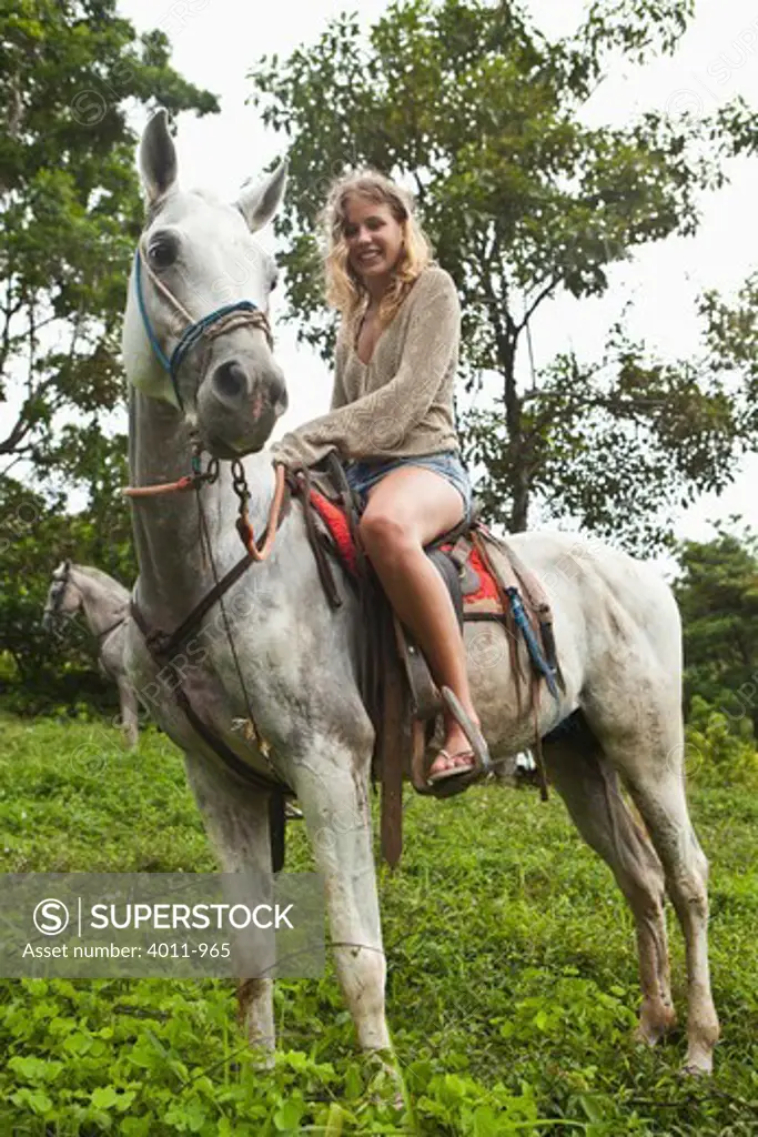 Woman riding a horse in the rainforest, Costa Rica