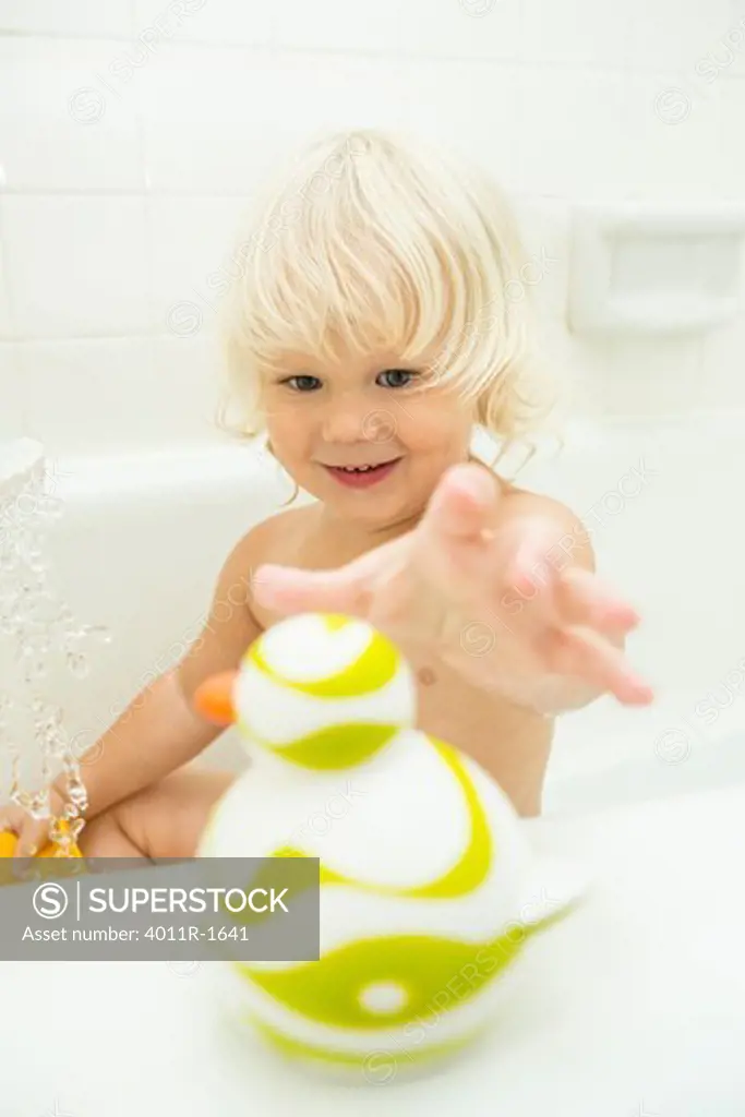 Young blonde boy in bath playing with rubber duck