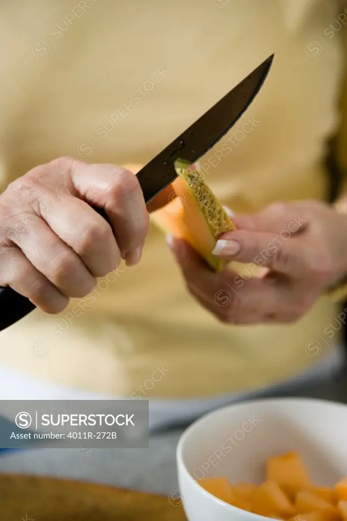 Elderly woman cutting a cantaloupe