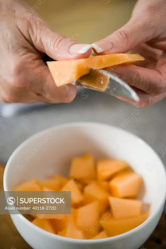 Elderly woman cutting a cantaloupe