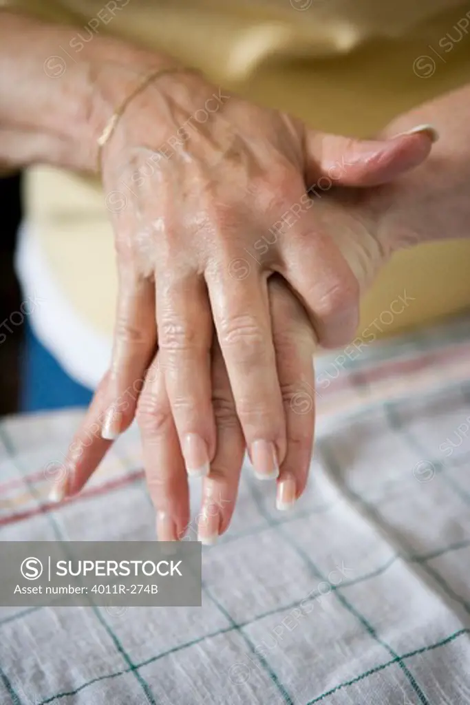 Elderly woman trying to put on lotion