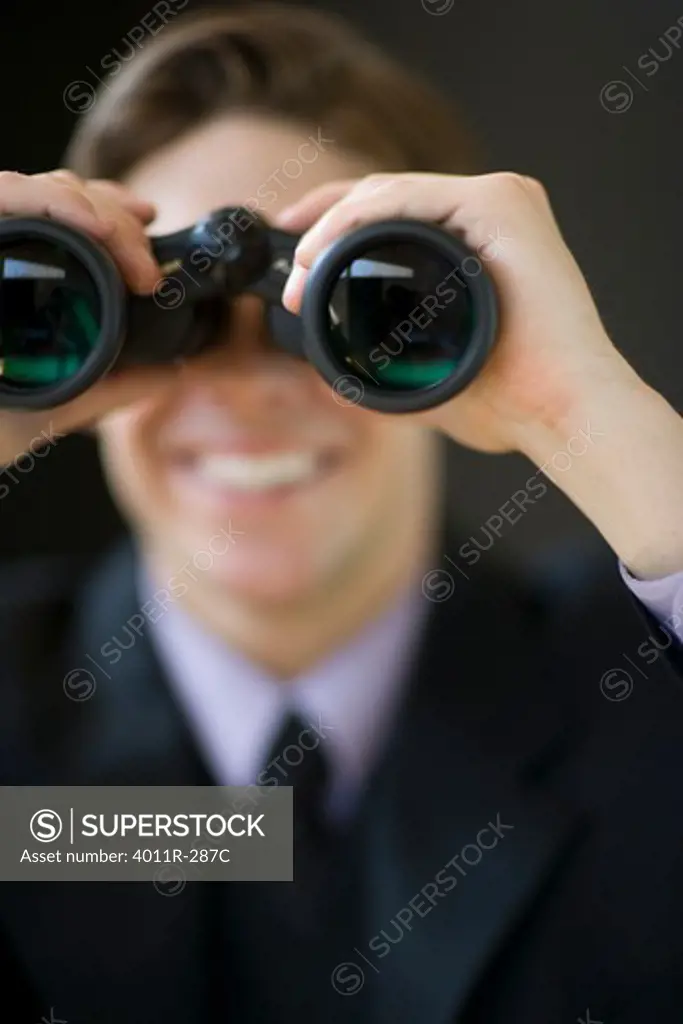 Young businessman holding binoculars