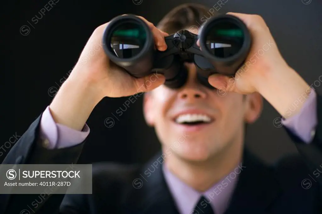 Young businessman holding binoculars