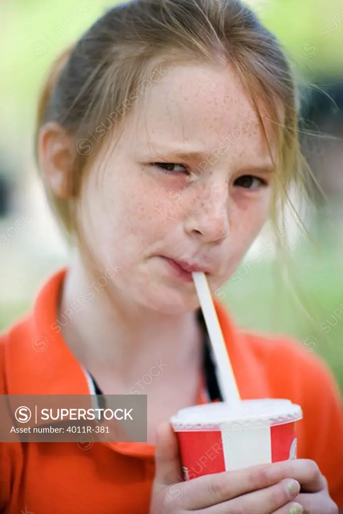 Girl drinking from a straw in a park, Texas, USA