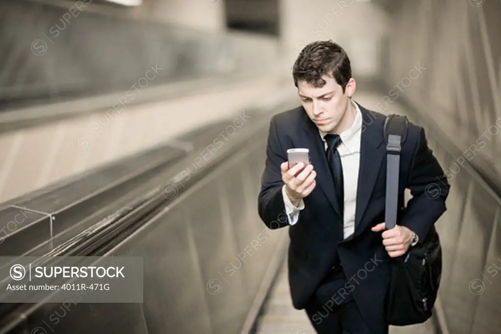 Businessman on escalator with cell phone