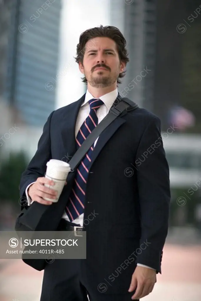 Businessman with coffee cup in street